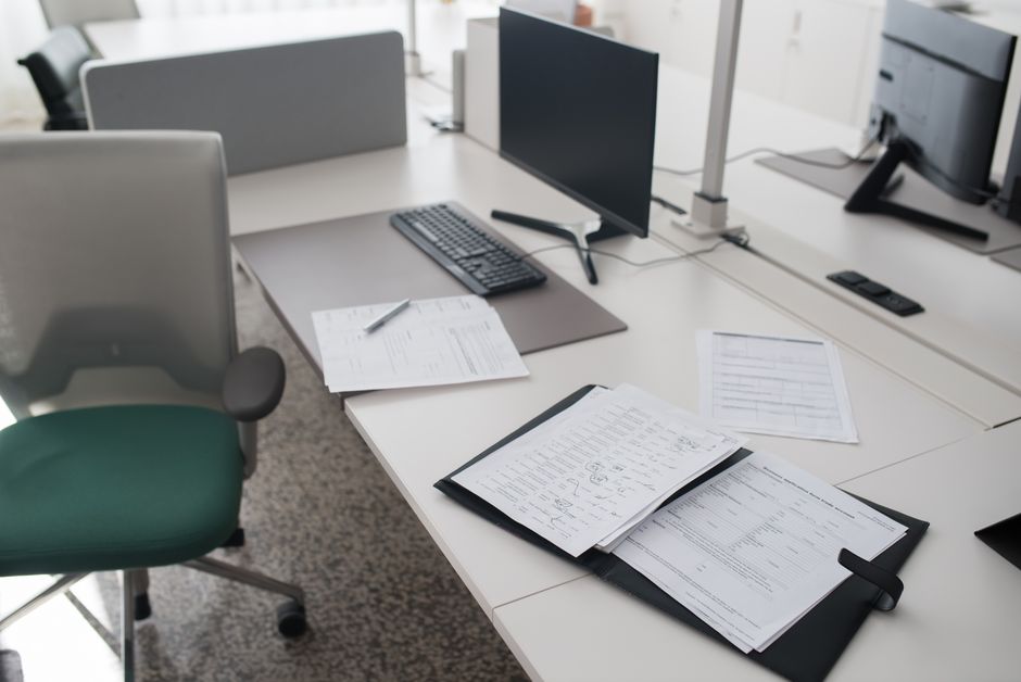 Stack of technical documents and drawings on a desk with a pen beside them
