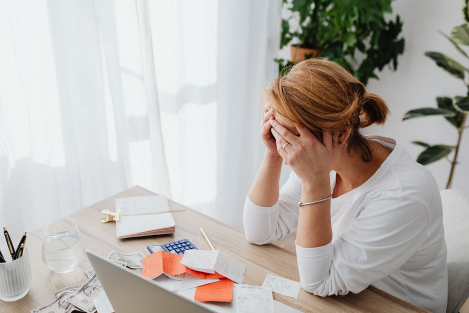 A homeowner frowning while reviewing a stack of bills and envelopes at home
