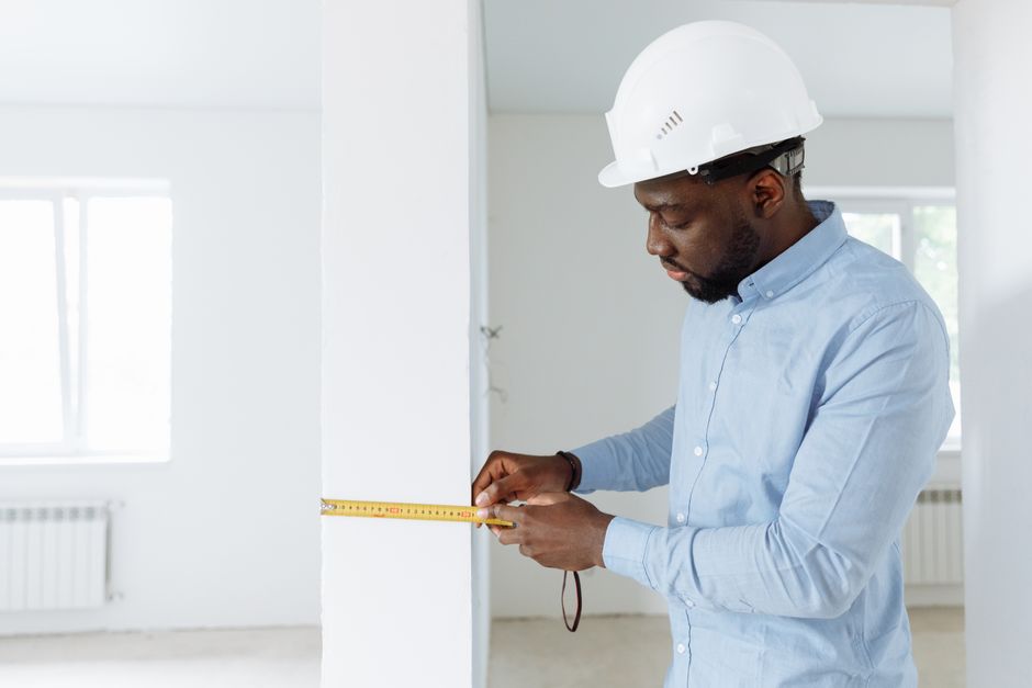 A county assessor with a clipboard measuring the exterior of a suburban house