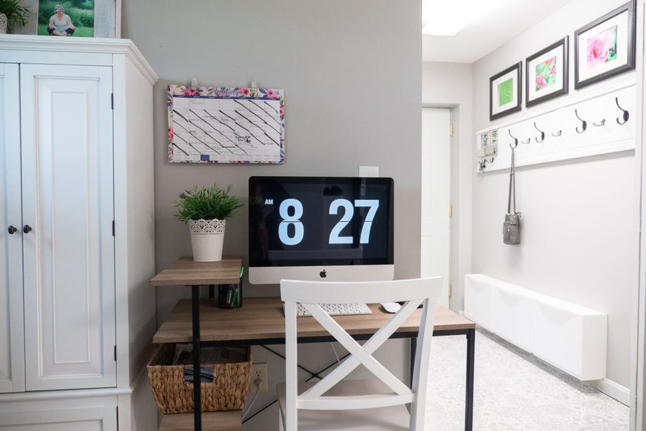 A wall calendar beside a clock in a plain office interior