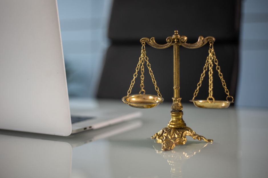 A small set of brass balance scales sitting on a wooden office desk