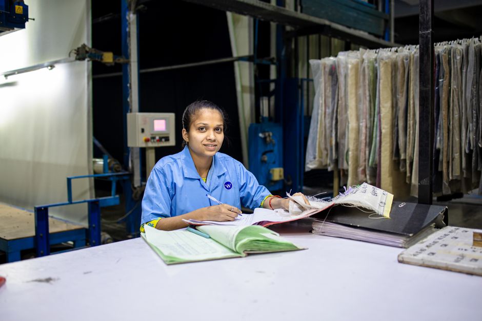 An office worker at a desk reading through a thick stack of paper files