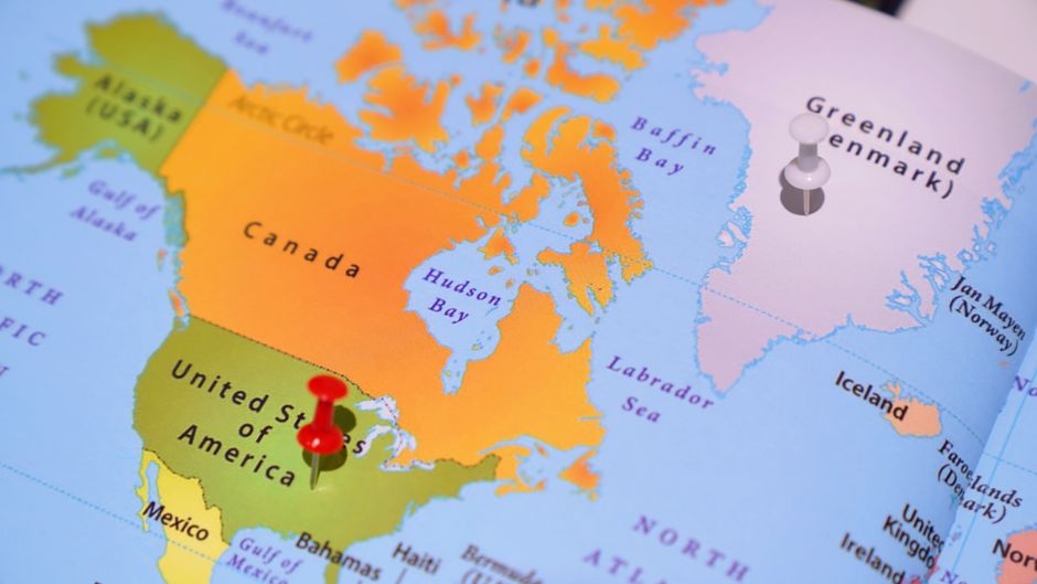 A paper map of the United States with colored pins marking several different states