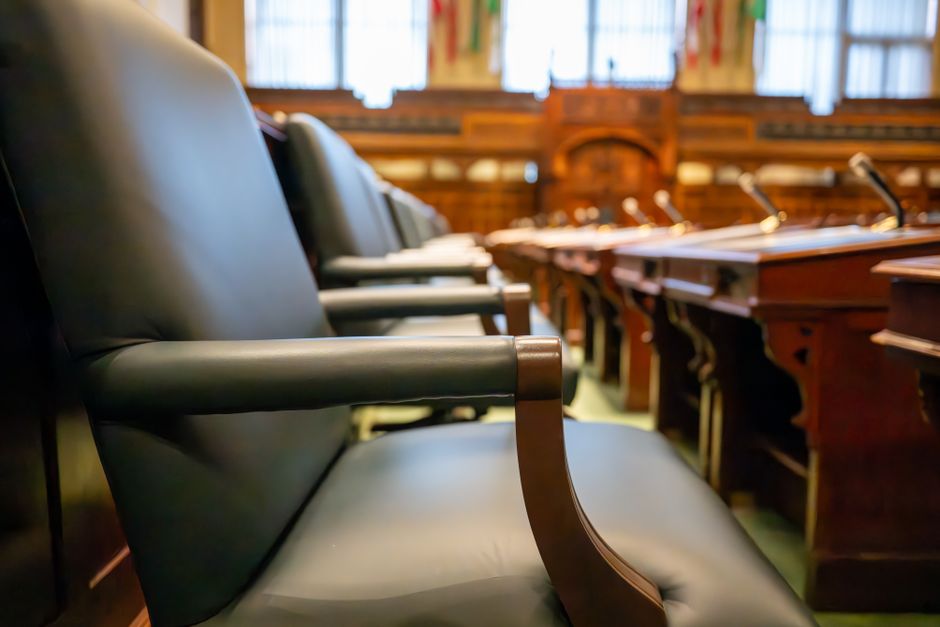An empty administrative hearing room with a long table, chairs, and a microphone