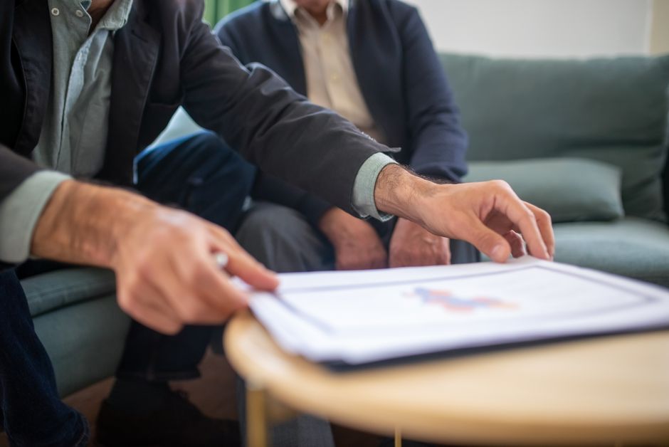 An adjuster at a desk reviewing printed medical and payroll documents with a laptop open